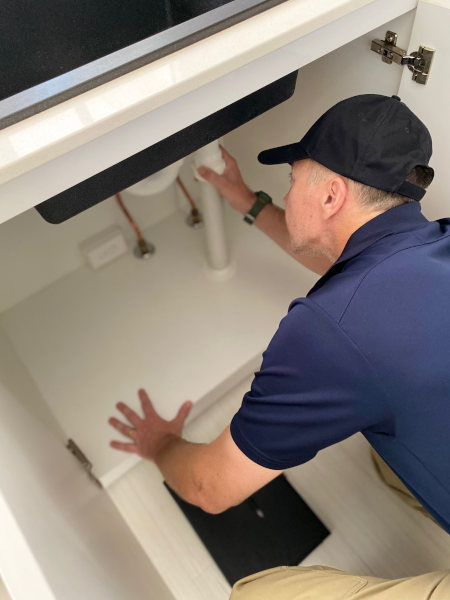 Man from Capstone Building Inspectors Cairns inspecting under a sink